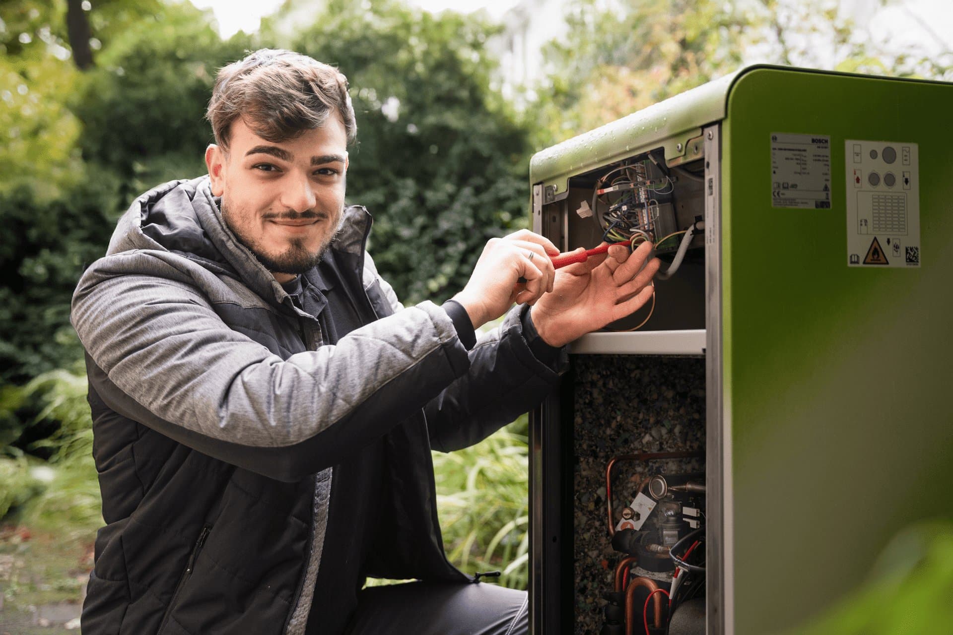 Techniker von FAENORA GmbH verdrahtet eine Bosch-Wärmepumpe im Garten